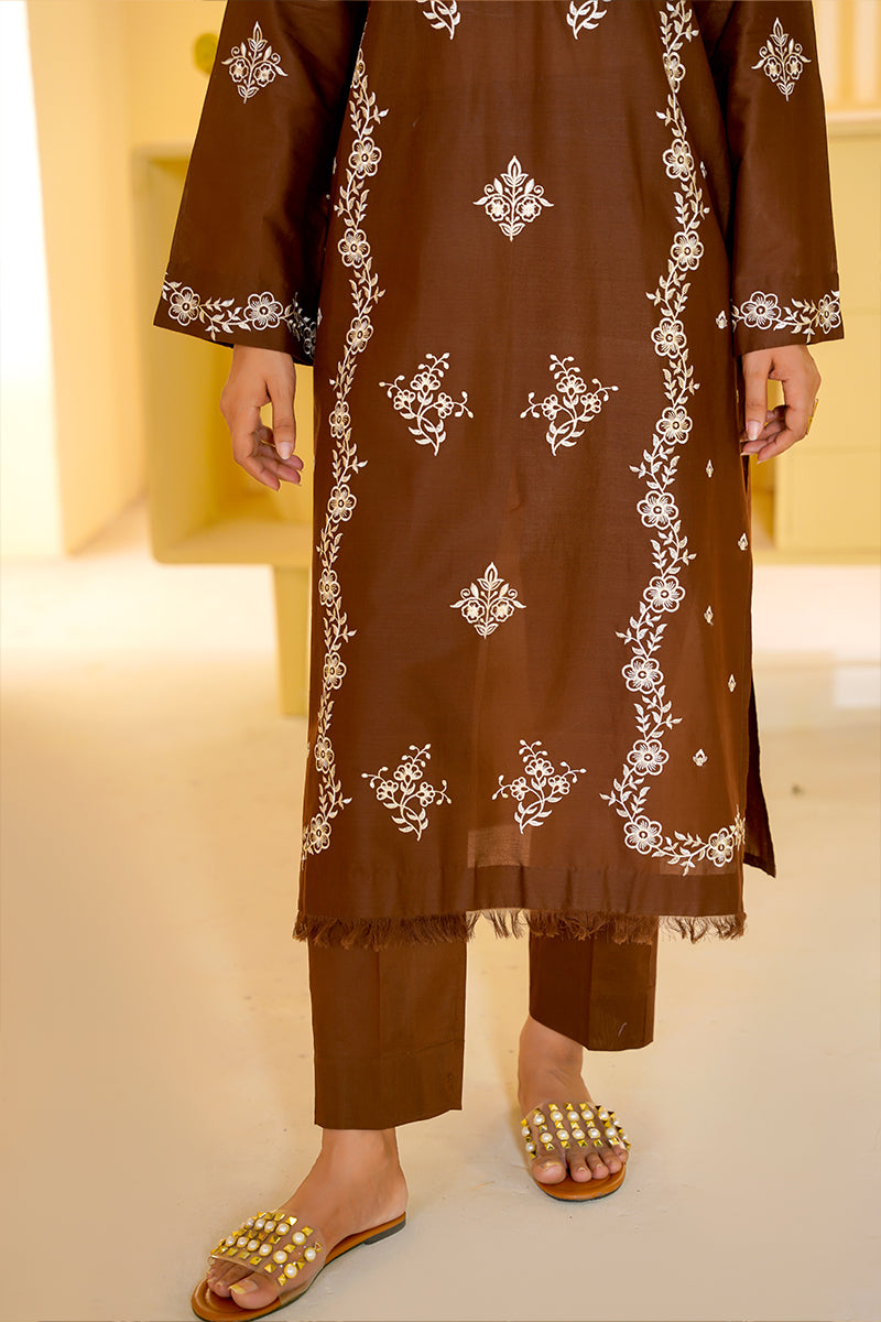Brown embroidered outfit with white patterns on a neutral background