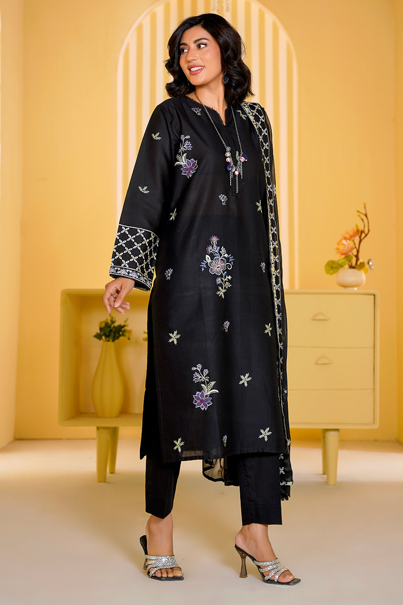 Woman wearing a black embroidered outfit in a bright yellow room.